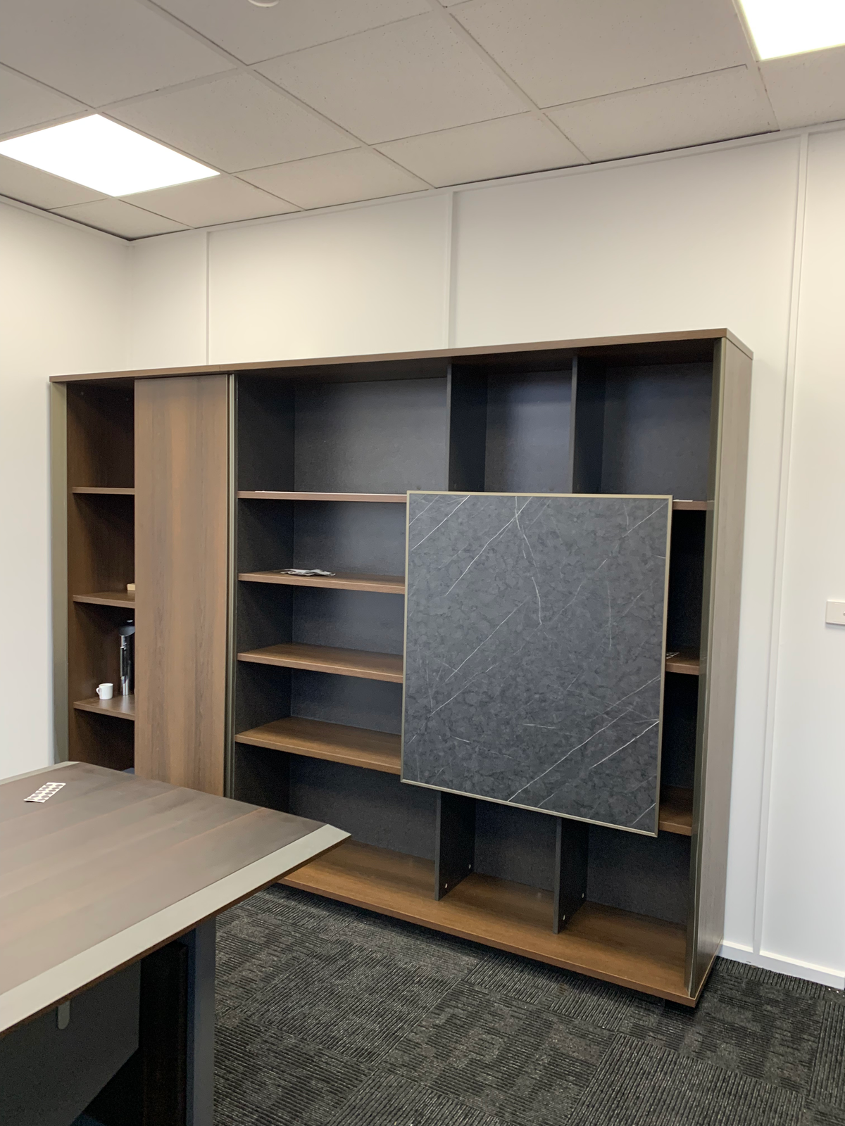 Wooden bookshelf with a marble panel in an office setting